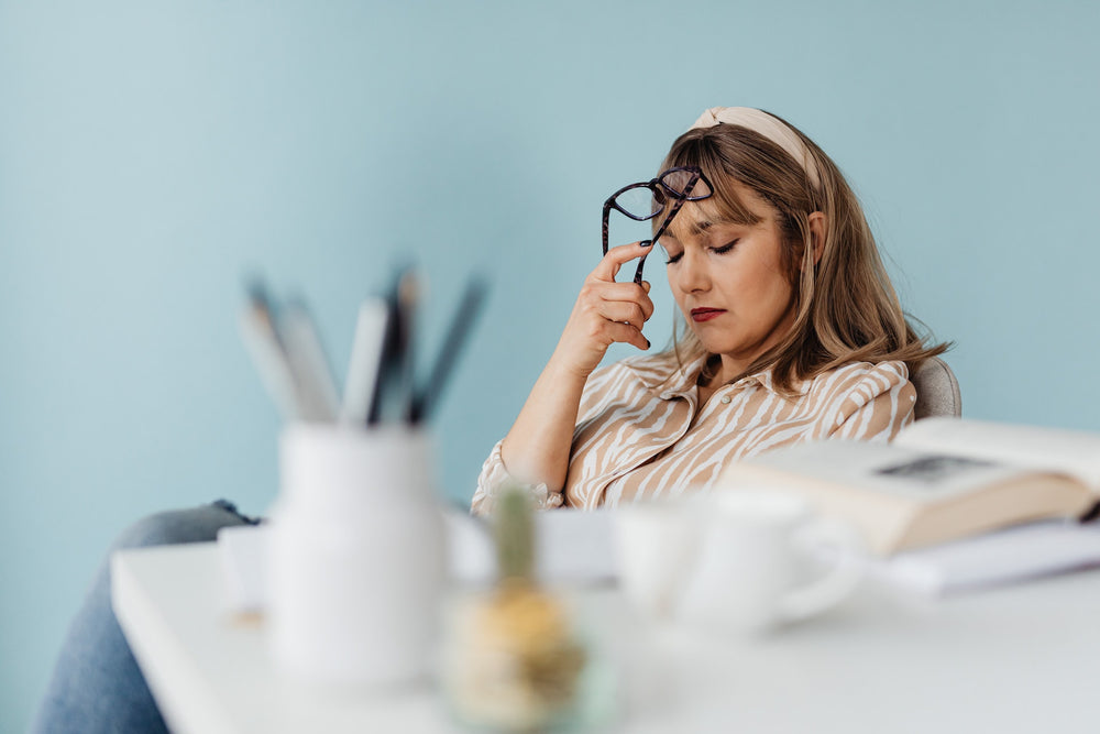 stressed woman tapping eyeglasses to her forehead