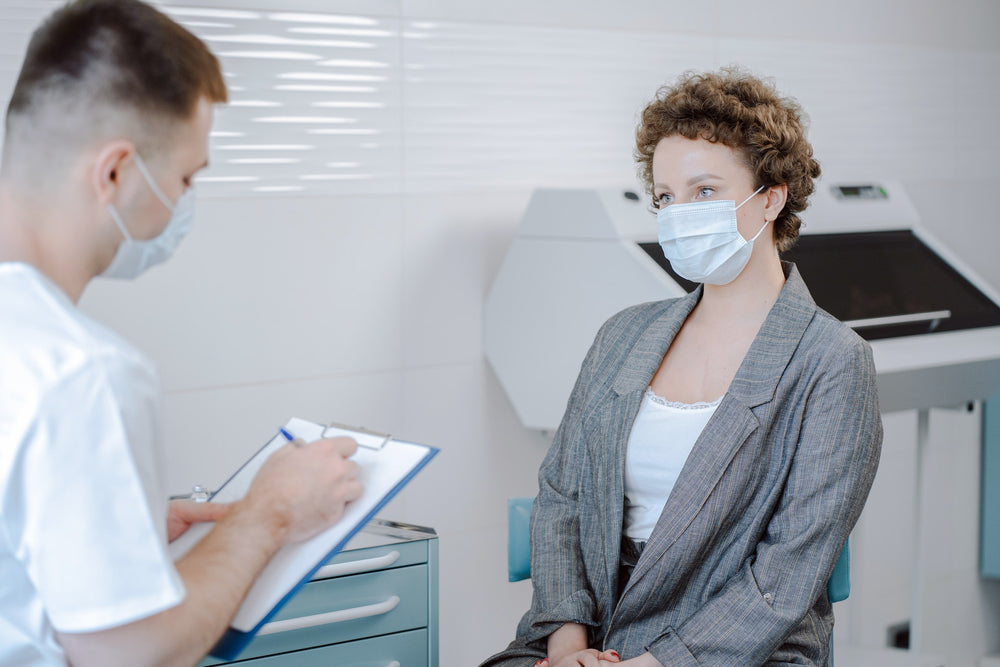 Woman in medical mask speaking to her doctor